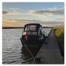 Ein Sportboot liegt an einem Anleger neben einer Wiese